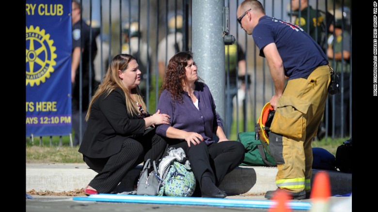 Women speak with firefighter at scene of shooting. Photo Courtesy of CNN.