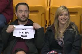 Guy holds up sign during kiss cam at hockey game. Image Courtesy of Youtube.com.