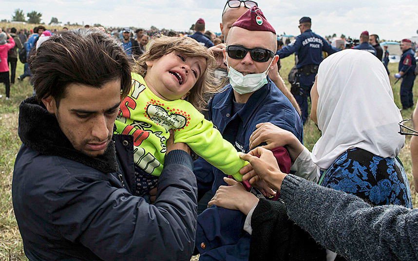 Migrants try to push past Hungarian police in Roszke. Image Courtesy of telegraph.co.uk.